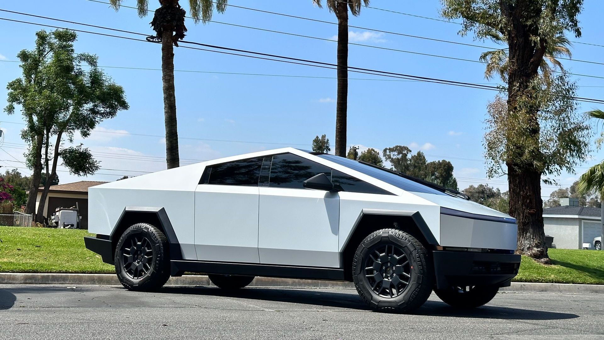 A white tesla cybertruck is parked on the side of the road.