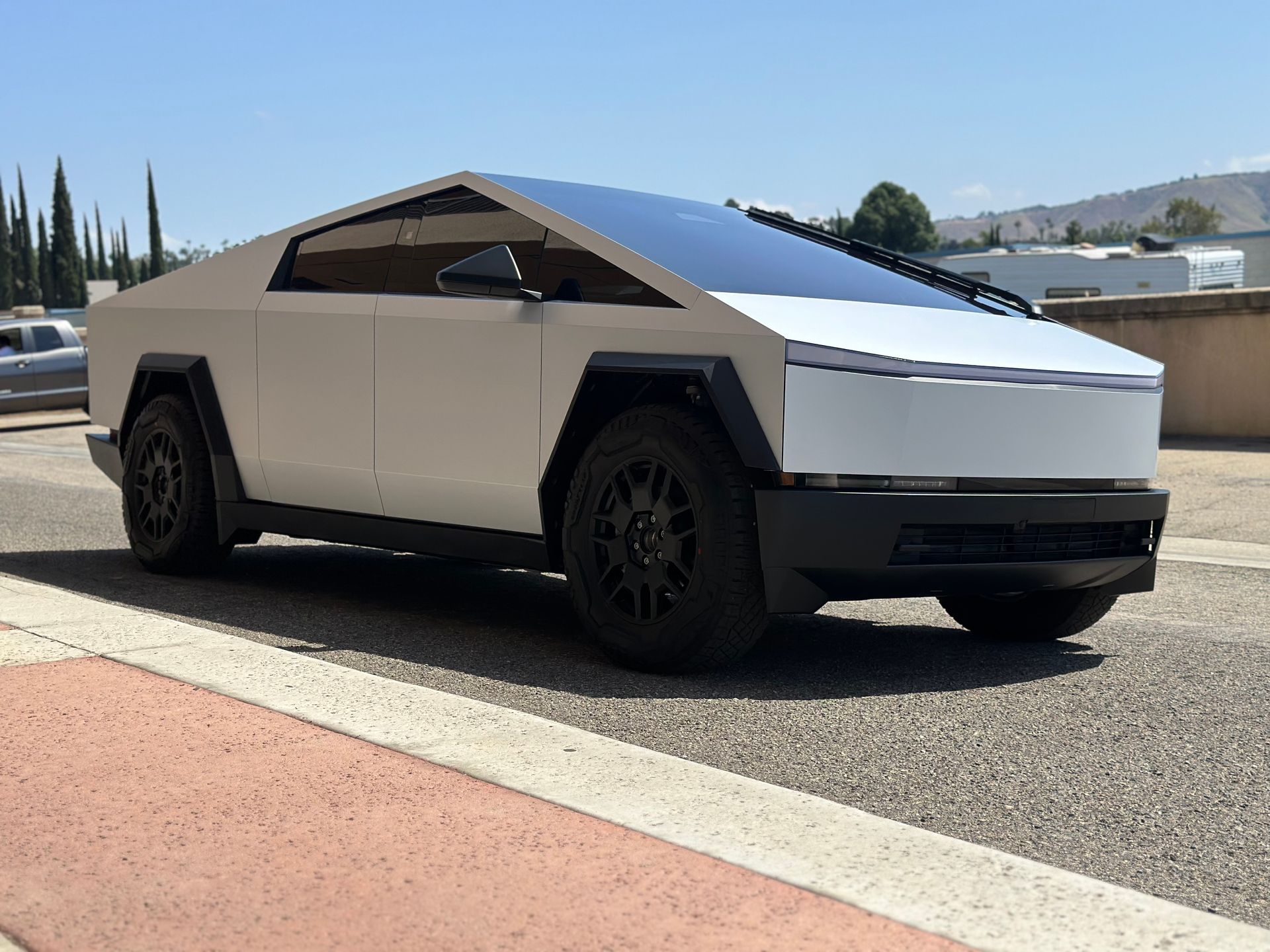 A white tesla cybertruck is parked on the side of the road