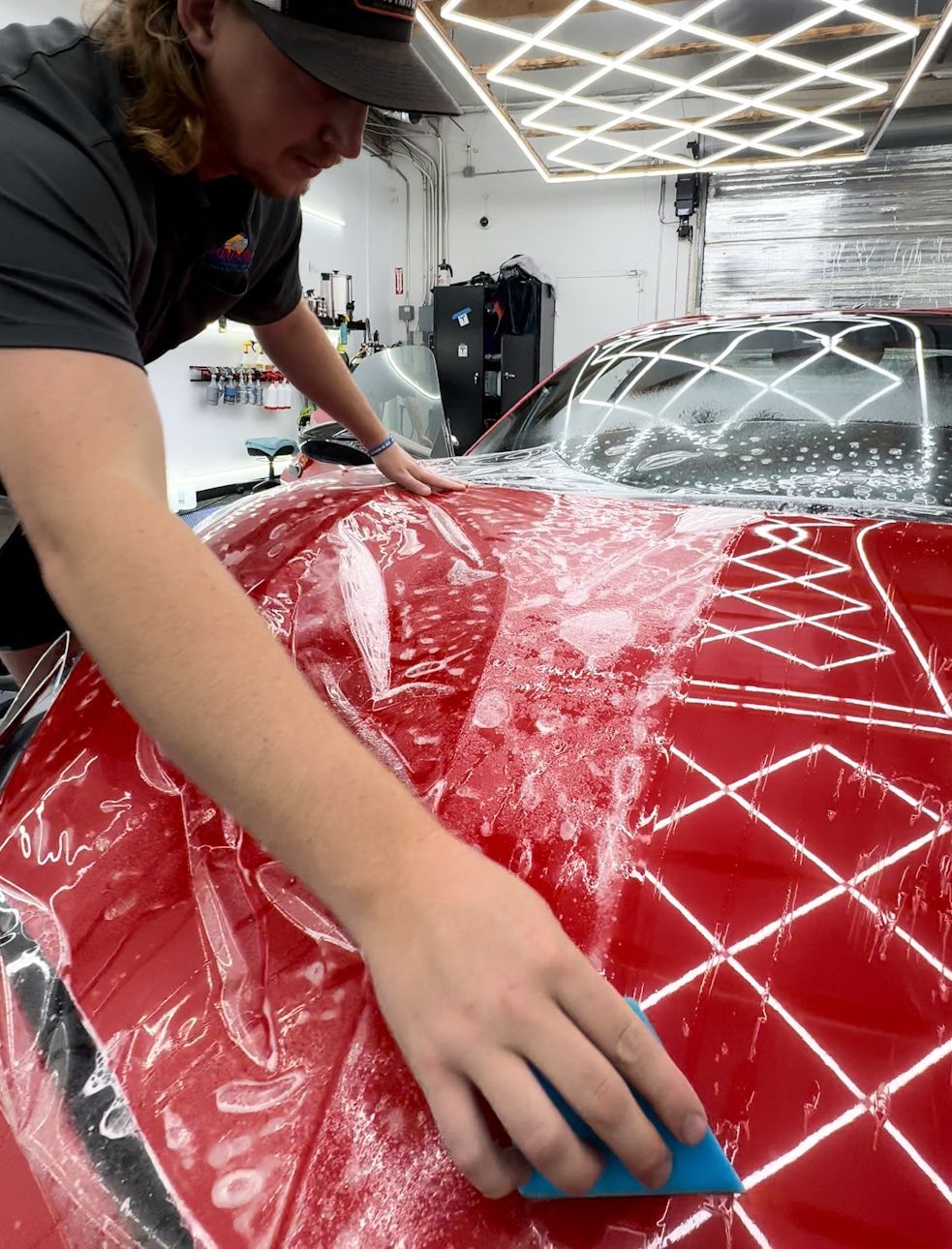 A man is cleaning the hood of a red car