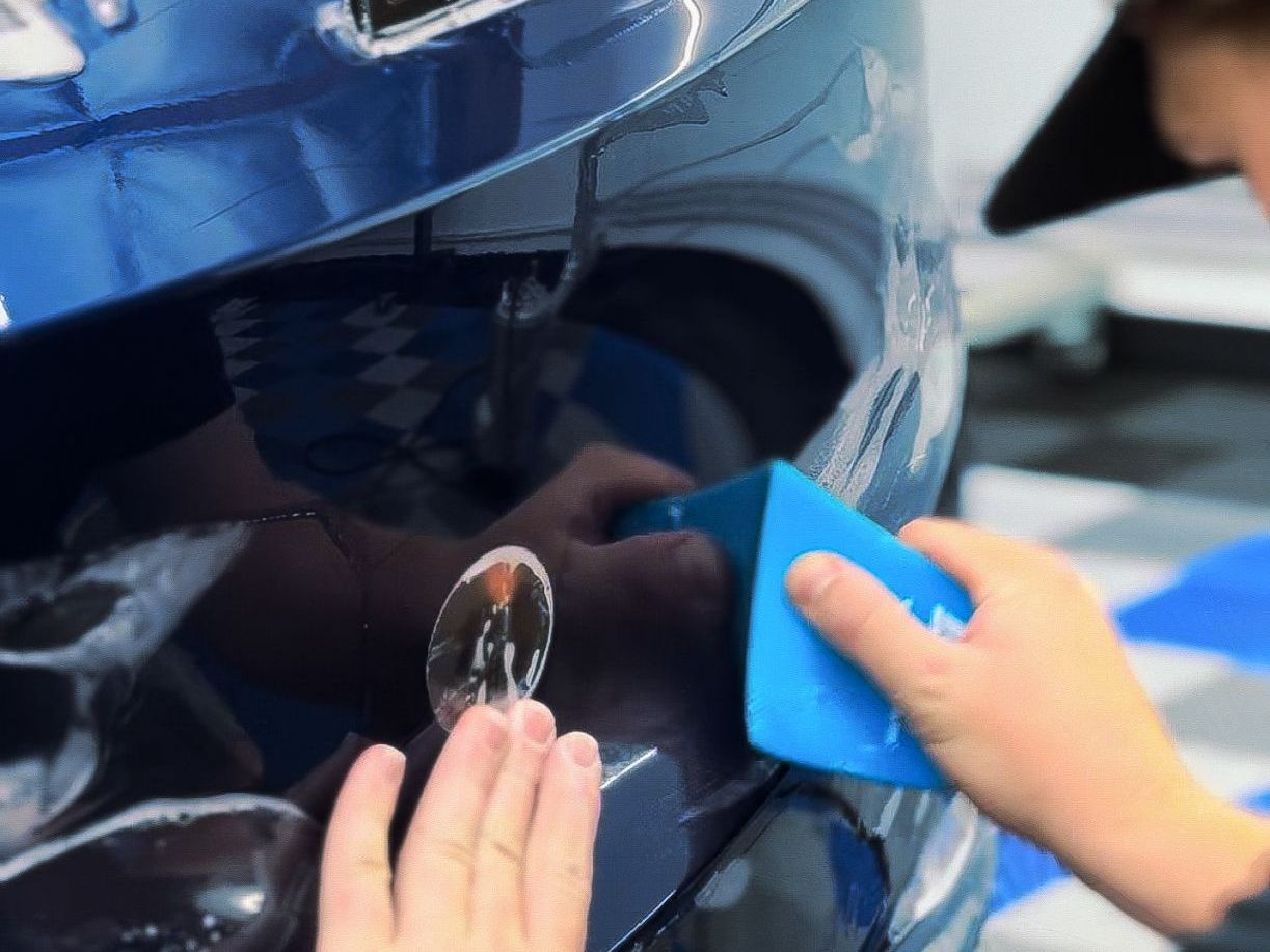 A person is applying a sticker to the side of a car.