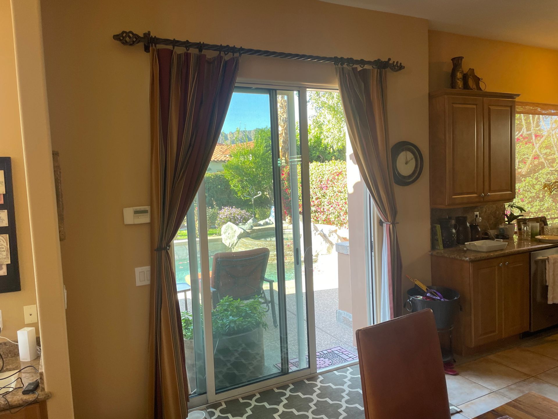 A kitchen with a sliding glass door and a clock on the wall.