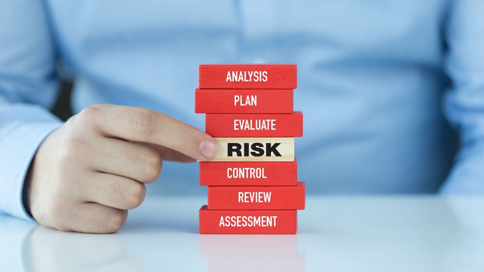 A person is holding a stack of red blocks with the word risk on top.