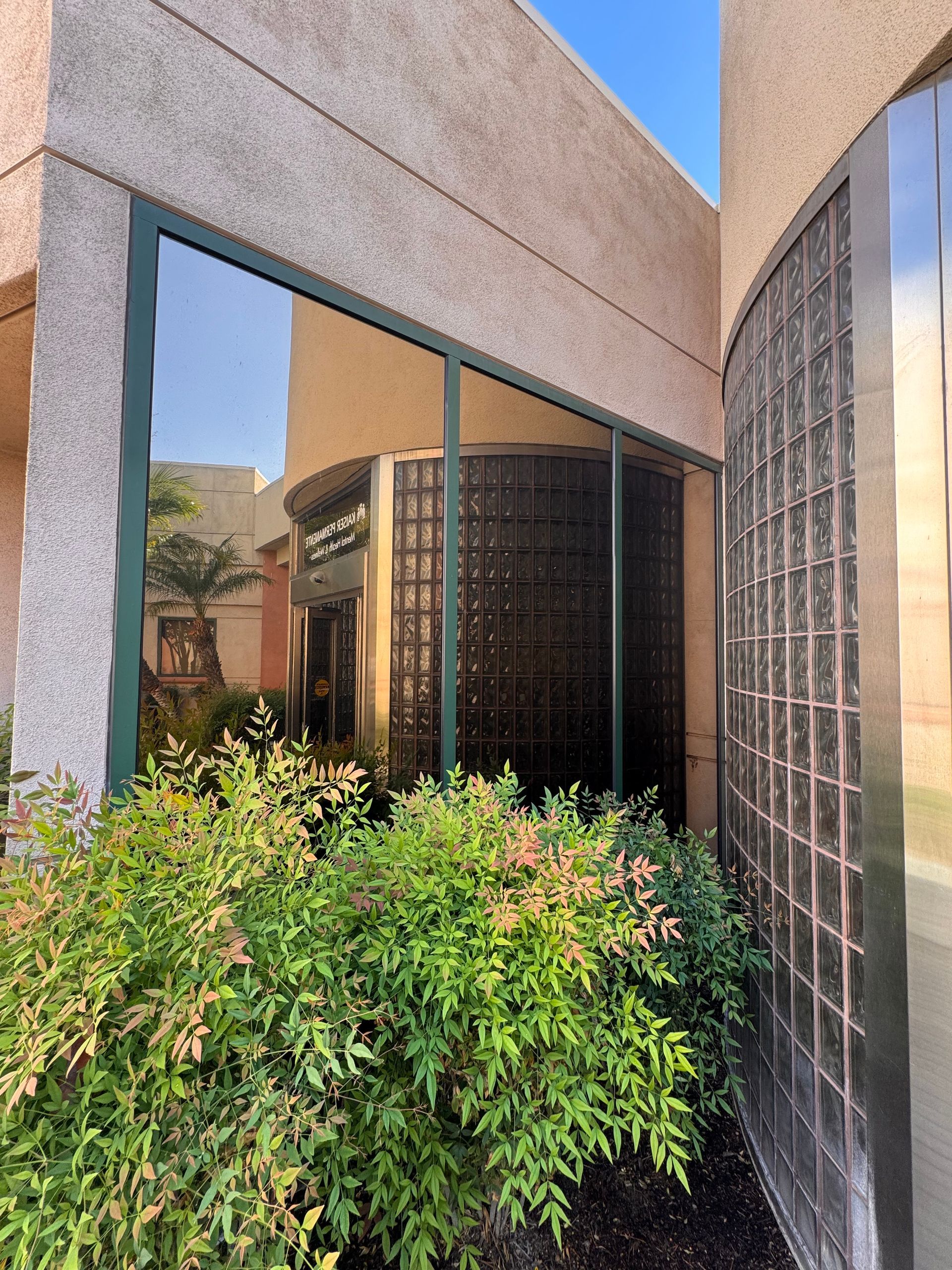 A building with a lot of windows and bushes in front of it