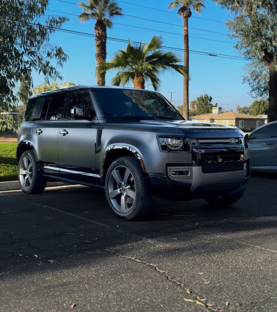 A silver bmw x5 is parked in front of a building.