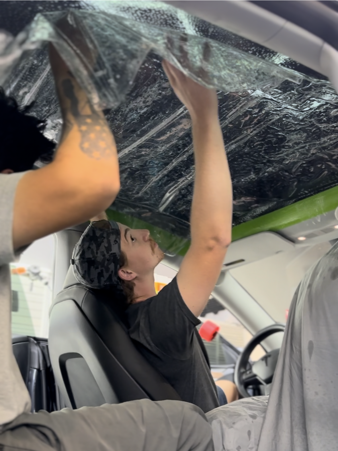 A man is covering the roof of a car with plastic