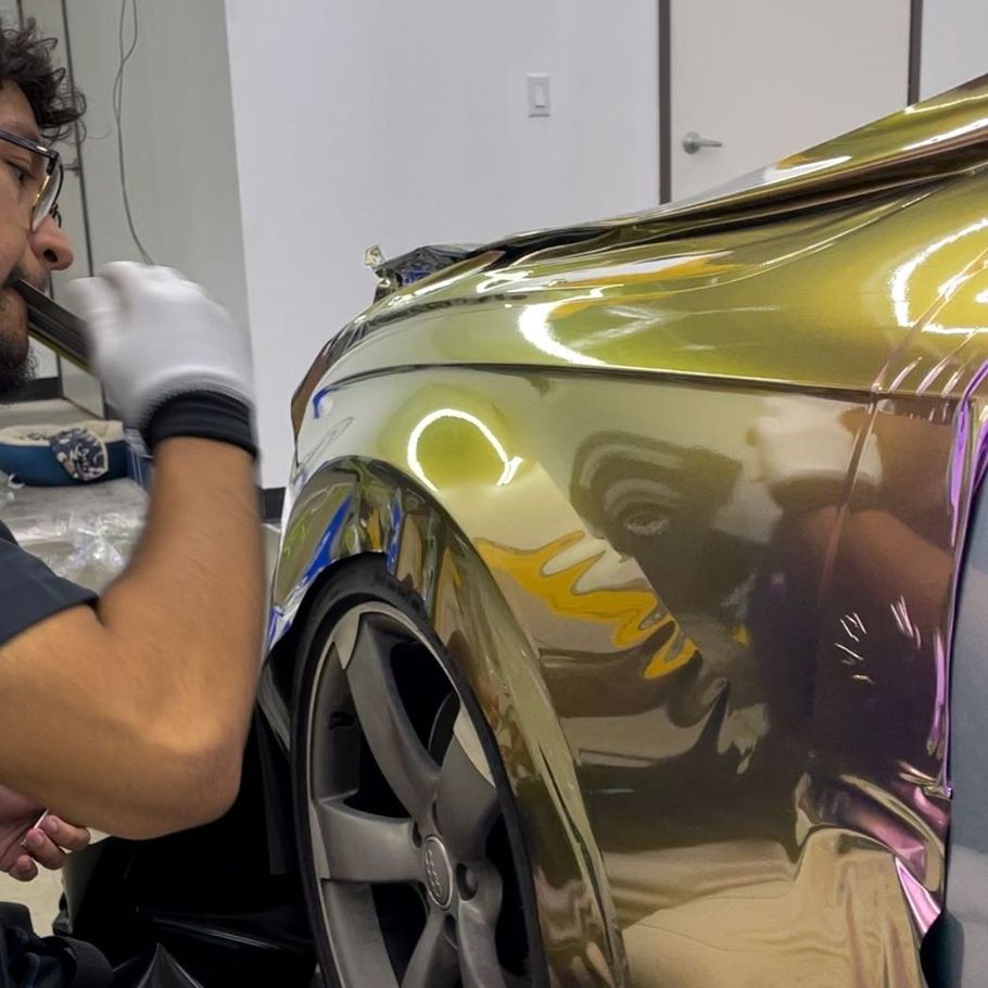 A man is wrapping a car in gold foil