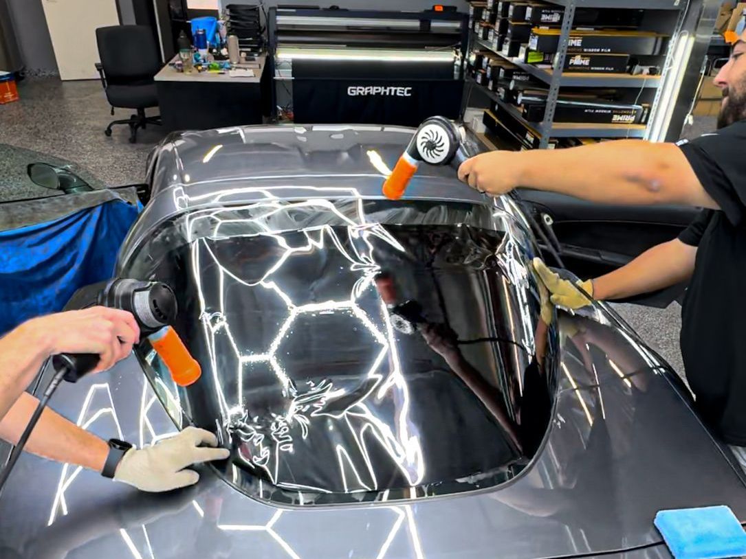 A group of people are working on a car in a garage.