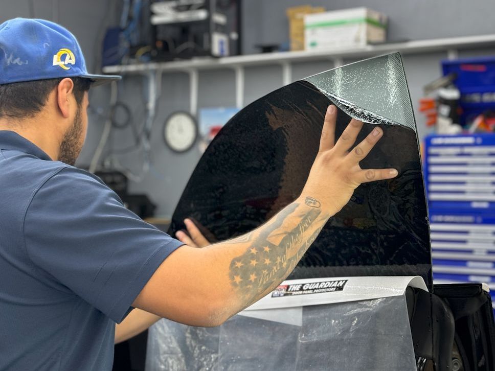 A man is applying window tinting to a car window.