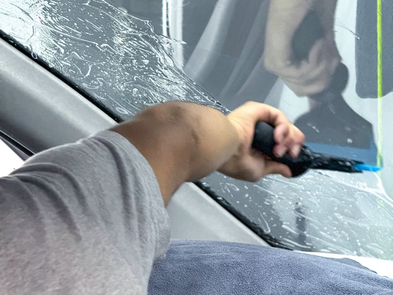 A person is cleaning a car windshield with a brush