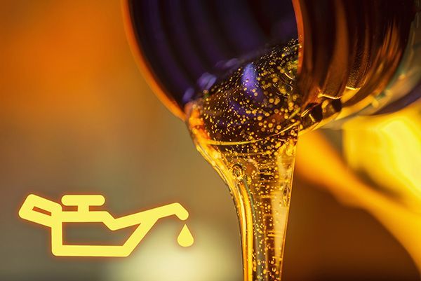 A close up of a bottle of oil being poured into a car.