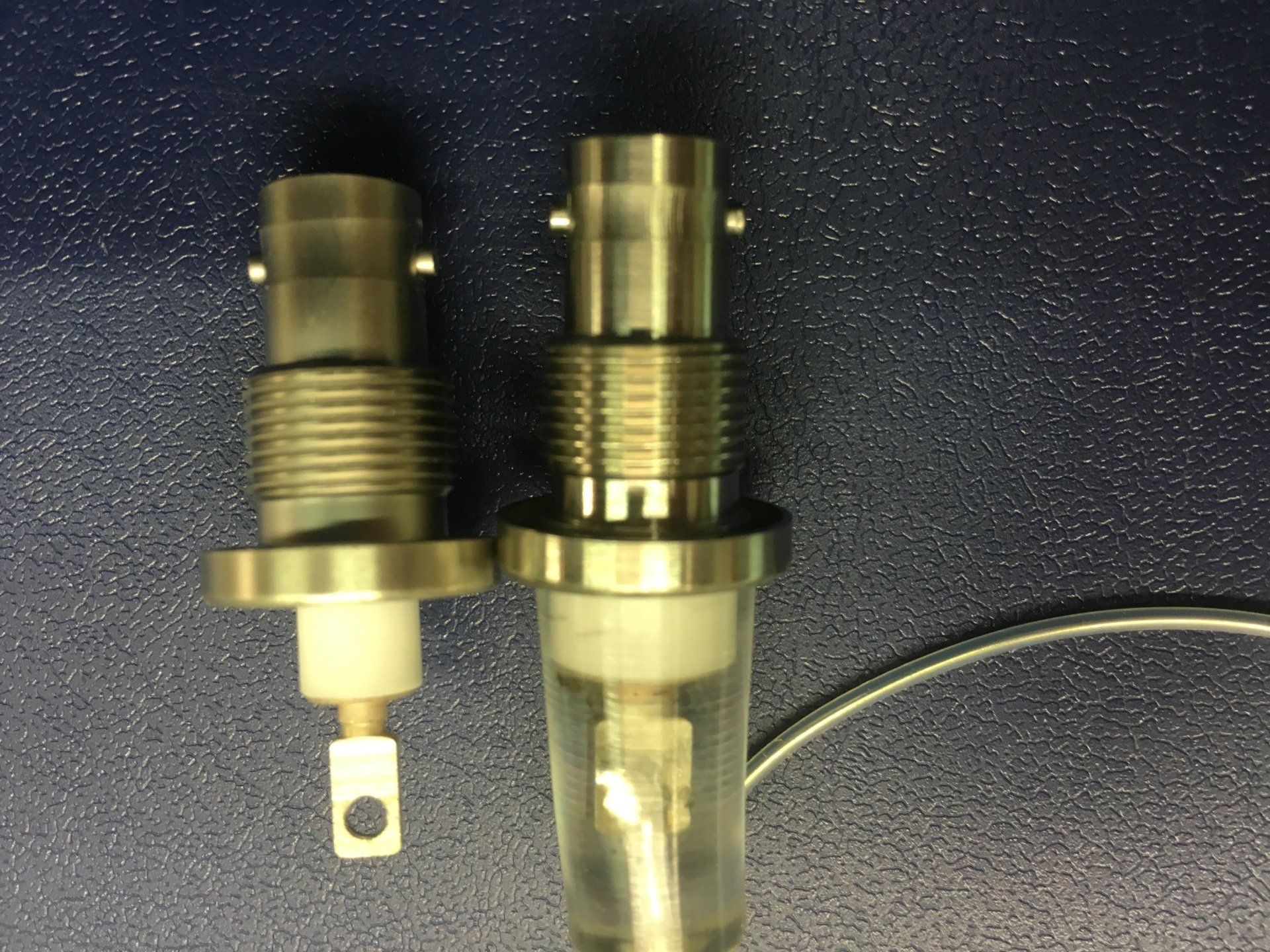 Two stainless steel connectors are sitting next to each other on a blue surface