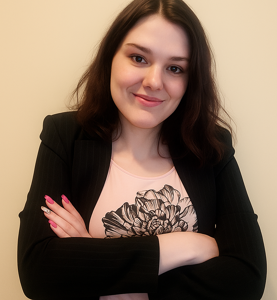 Woman with crossed arms, wearing a black blazer over a pink shirt with a print, smiles against a beige background.