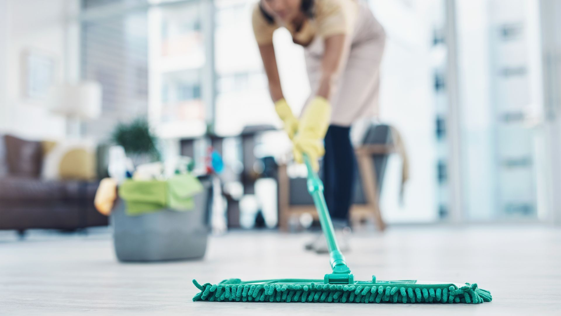 A woman is cleaning the floor with a mop in a living room.