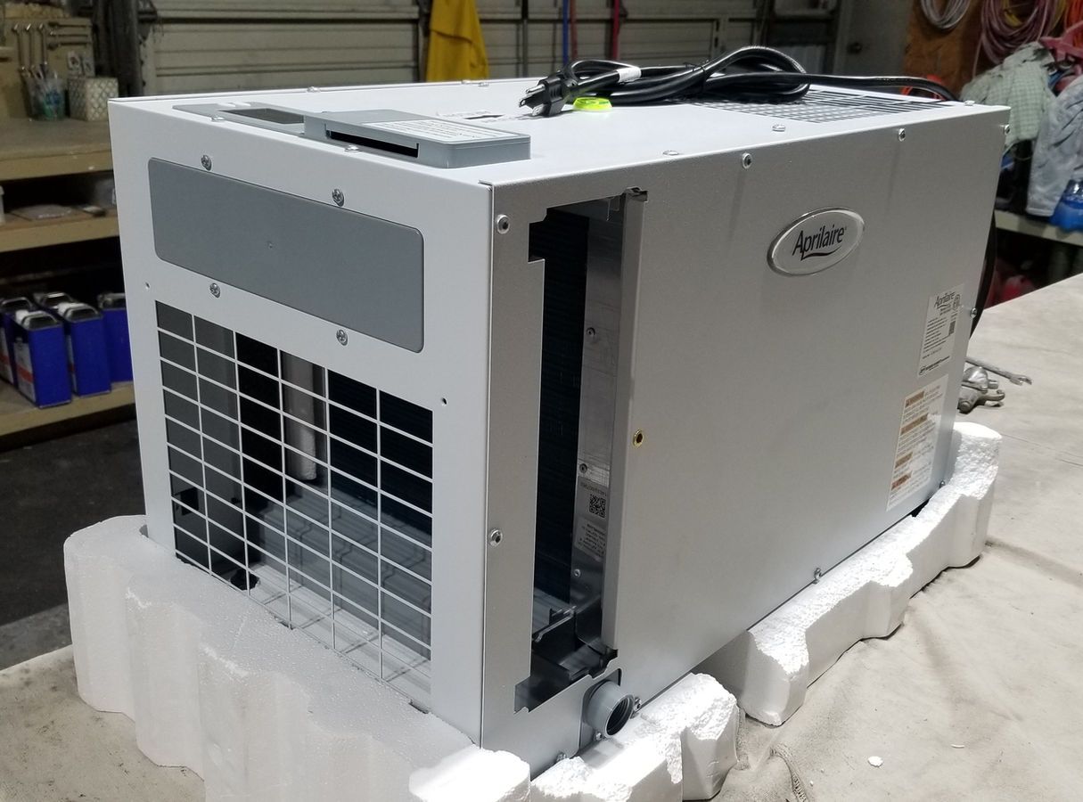 A gray industrial cooler sitting on white foam packaging, in a workshop setting.