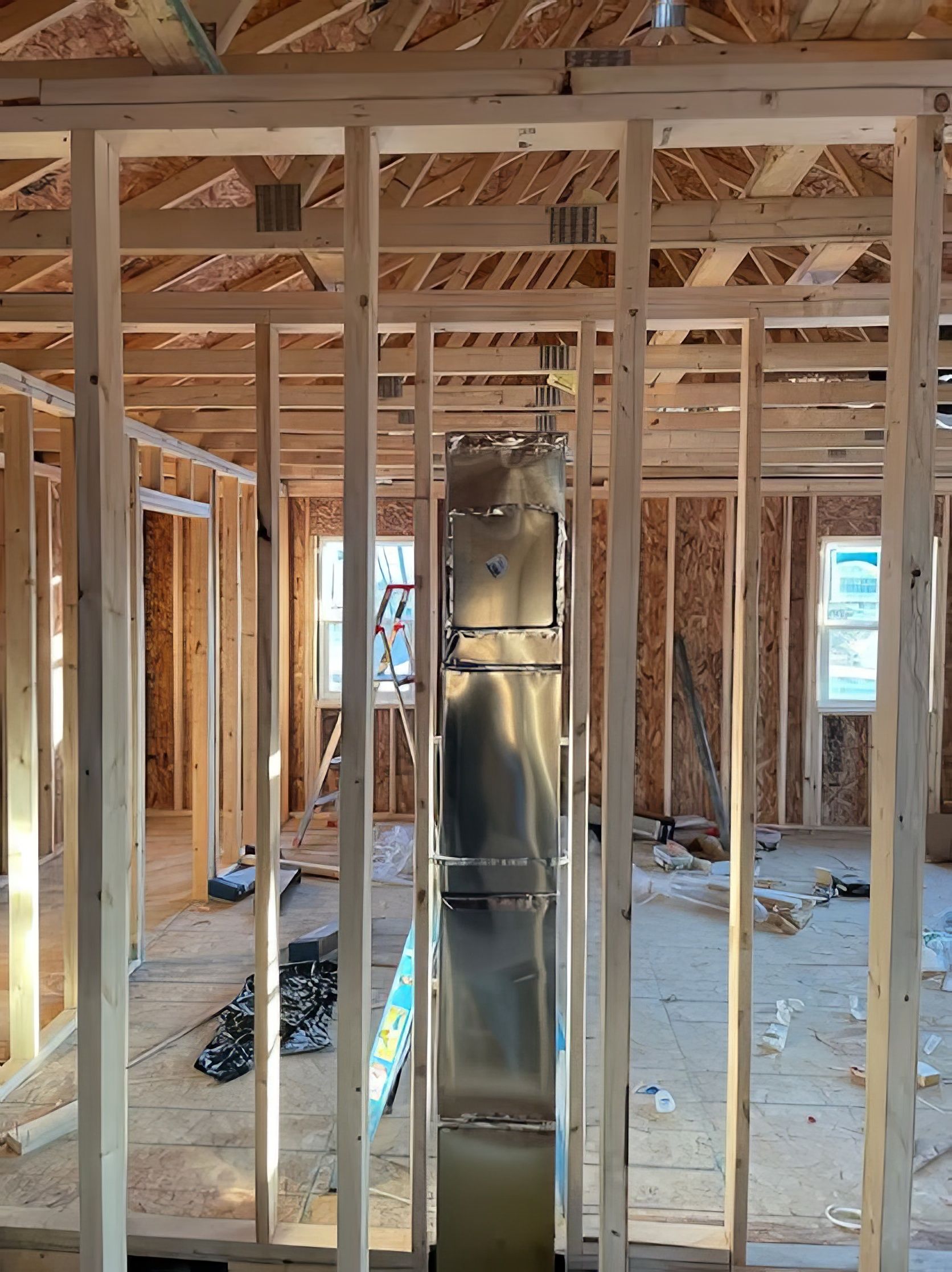 Wooden framing of a house under construction with a central rectangular metal duct.