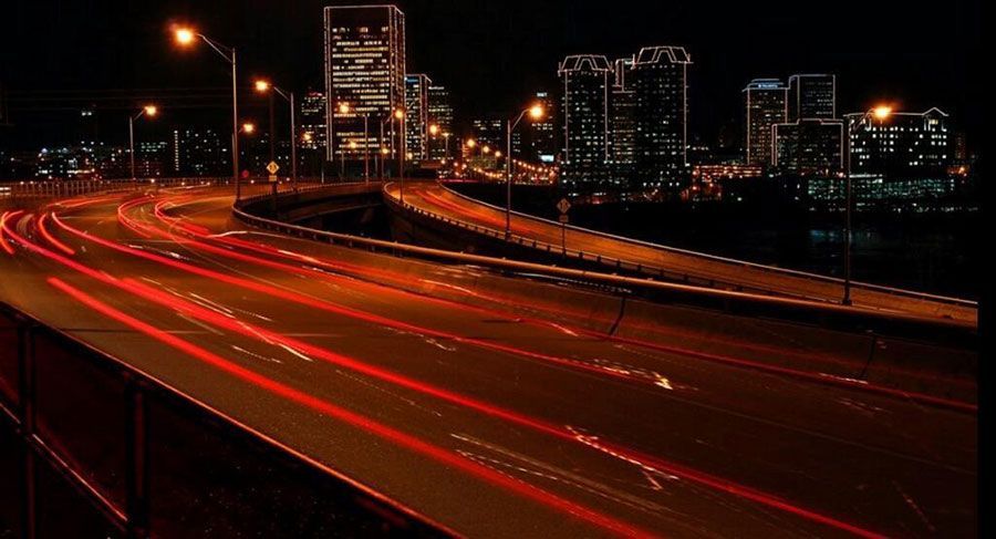 A long exposure photo of a highway at night with a city in the background.