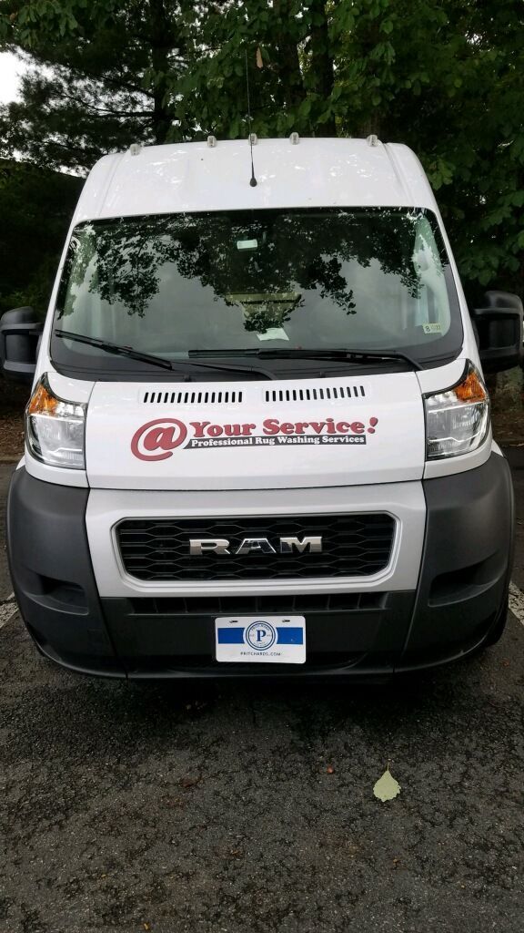 A white ram van is parked in a parking lot.