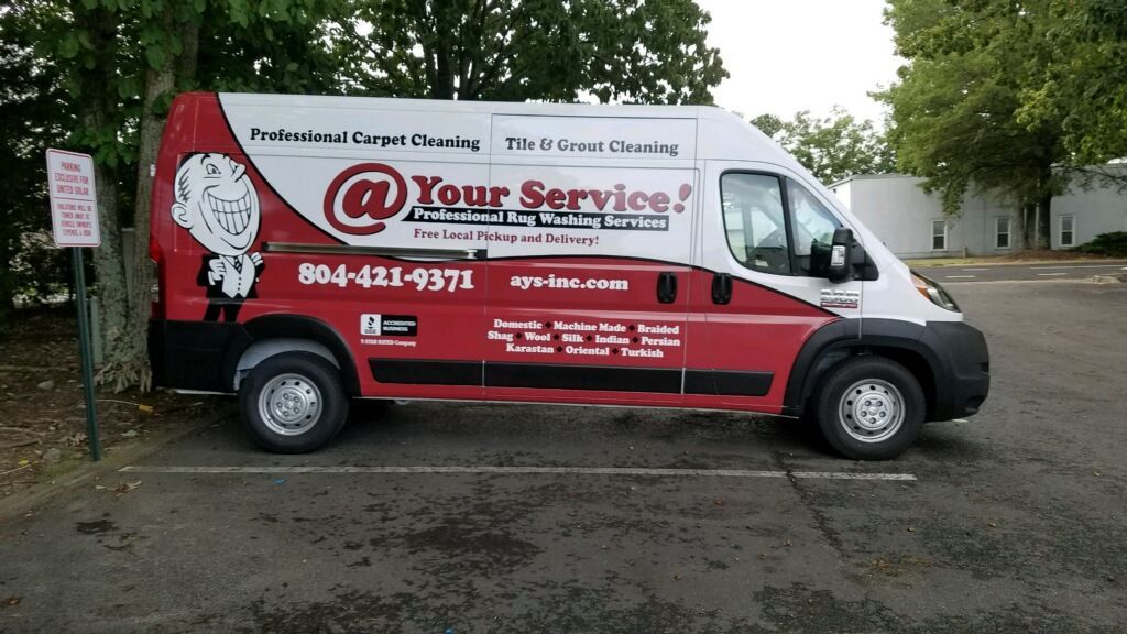 A red and white van that says your service is parked in a parking lot