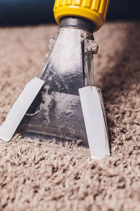 A close up of a vacuum cleaner cleaning a carpet.