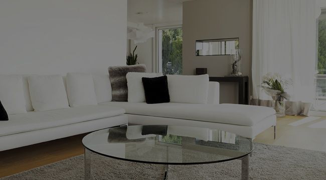 A living room with two white couches and a glass coffee table.