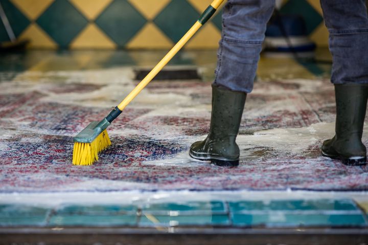 A vacuum cleaner is being used to clean a rug.