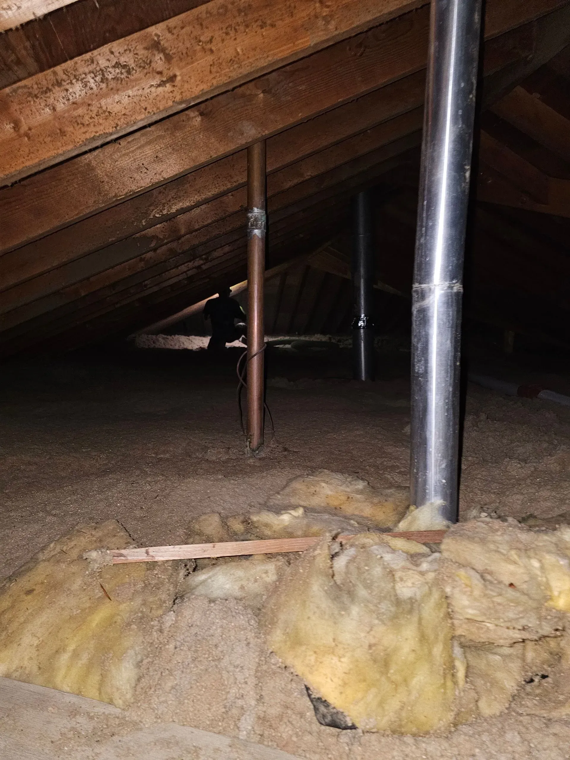 An attic with a metal pipe in the middle of it