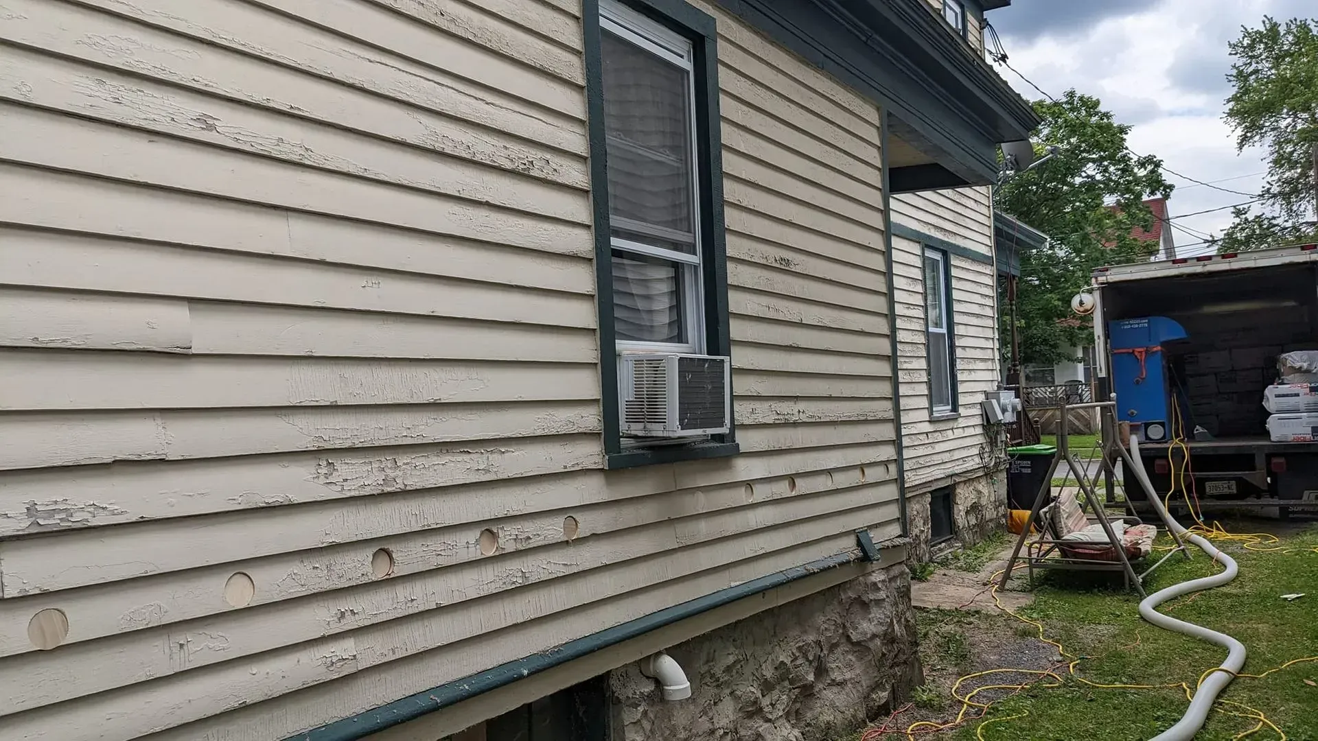 A white house with a hose attached to the side of it.