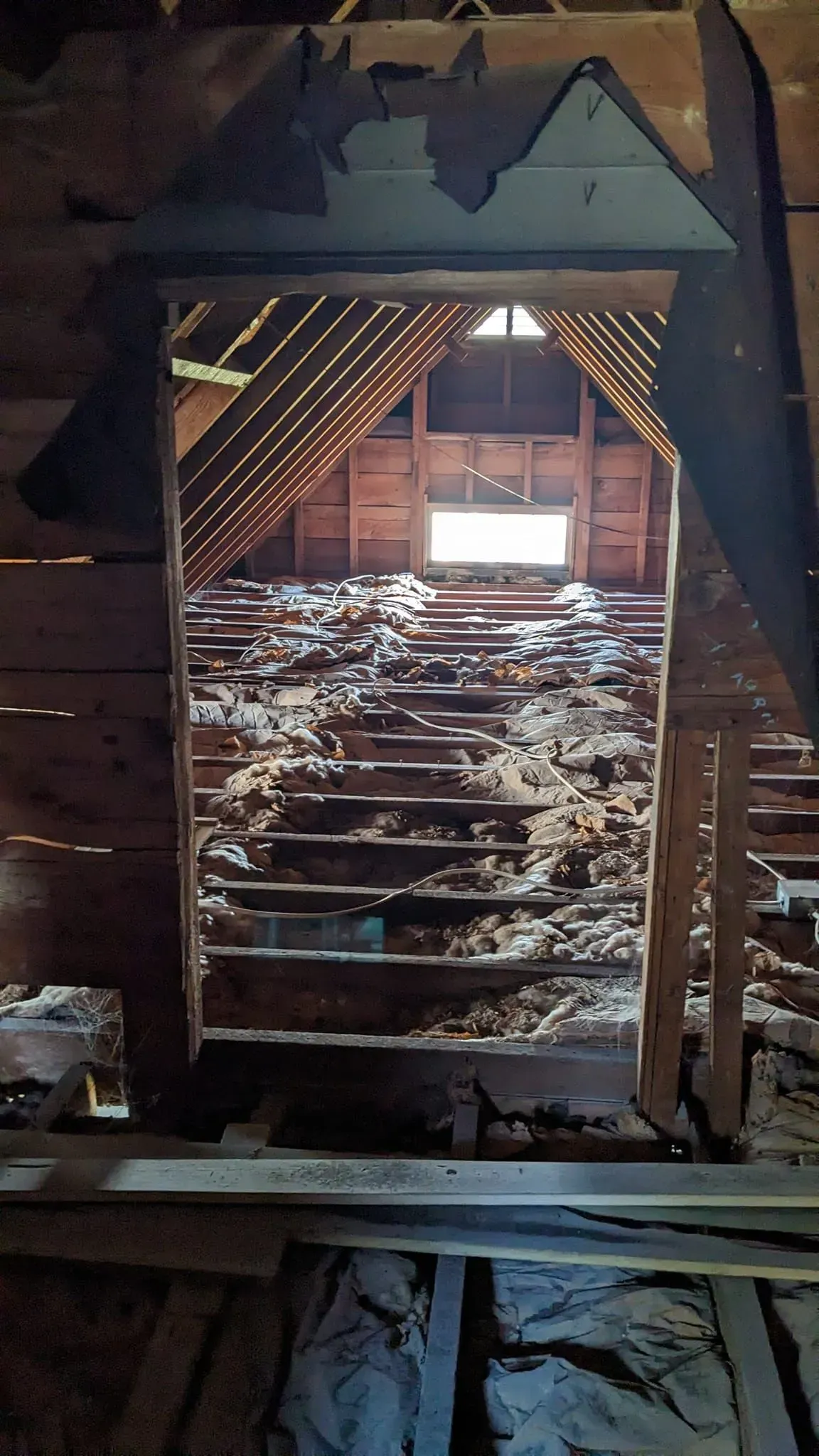 There is a window in the attic of a building.