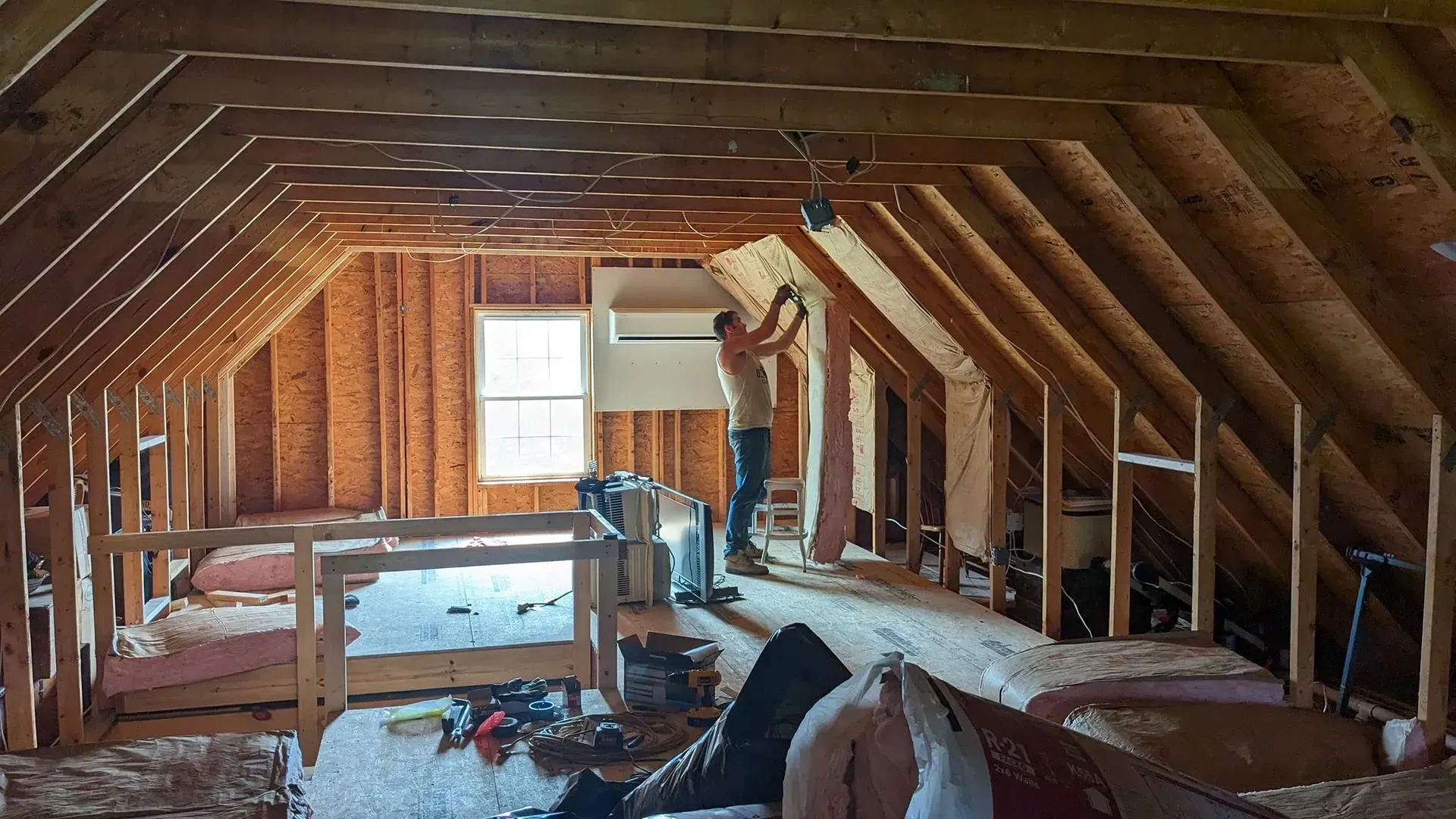 A man is working on the attic of a house under construction.