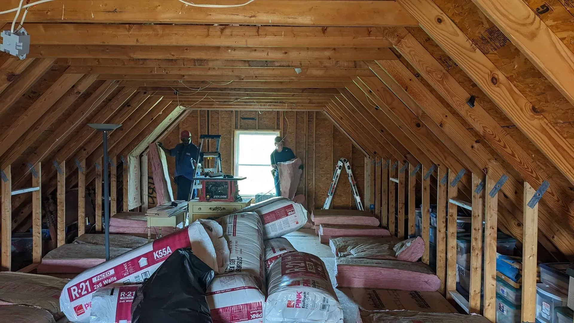 A man is standing in the attic of a house.
