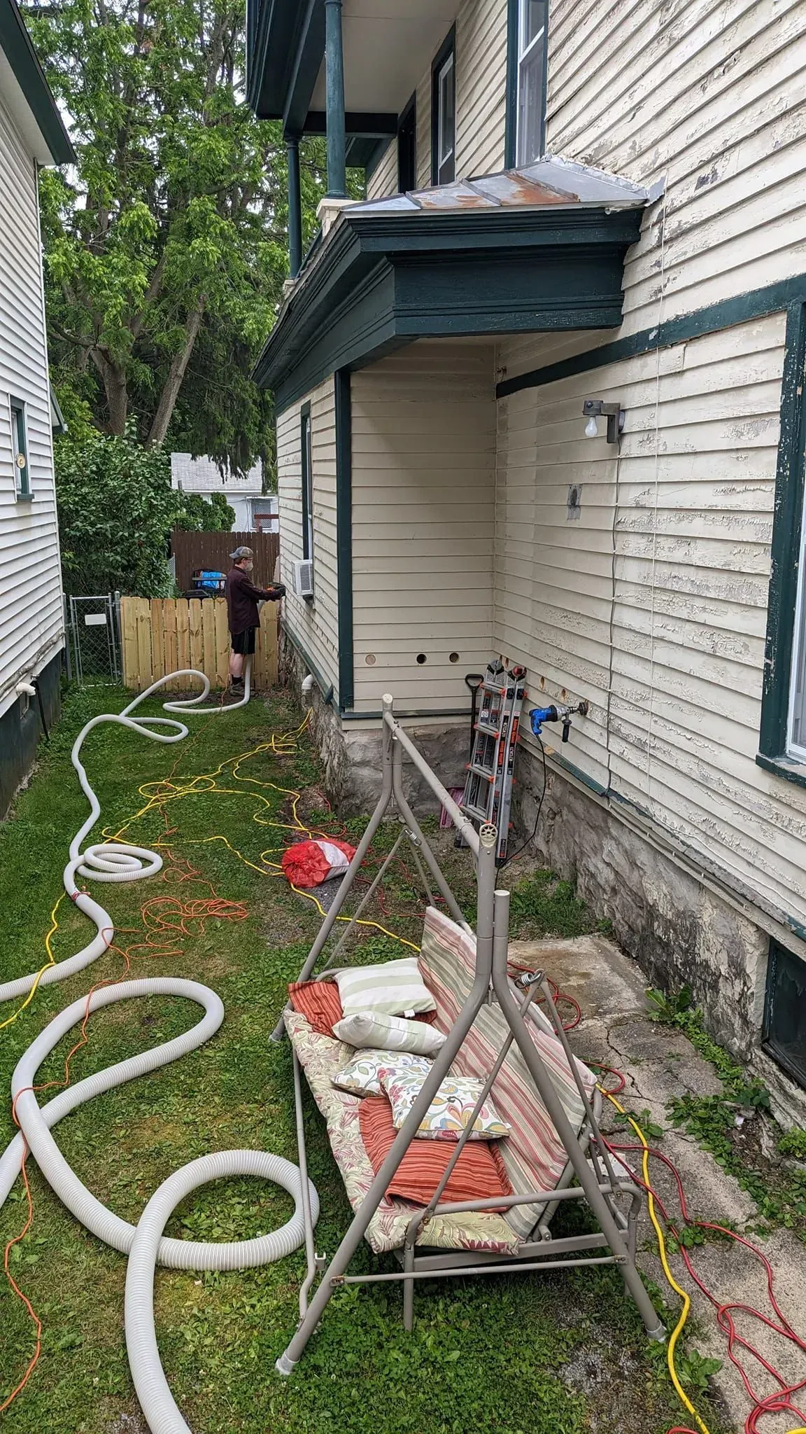 A man is working on the side of a house with a hose.