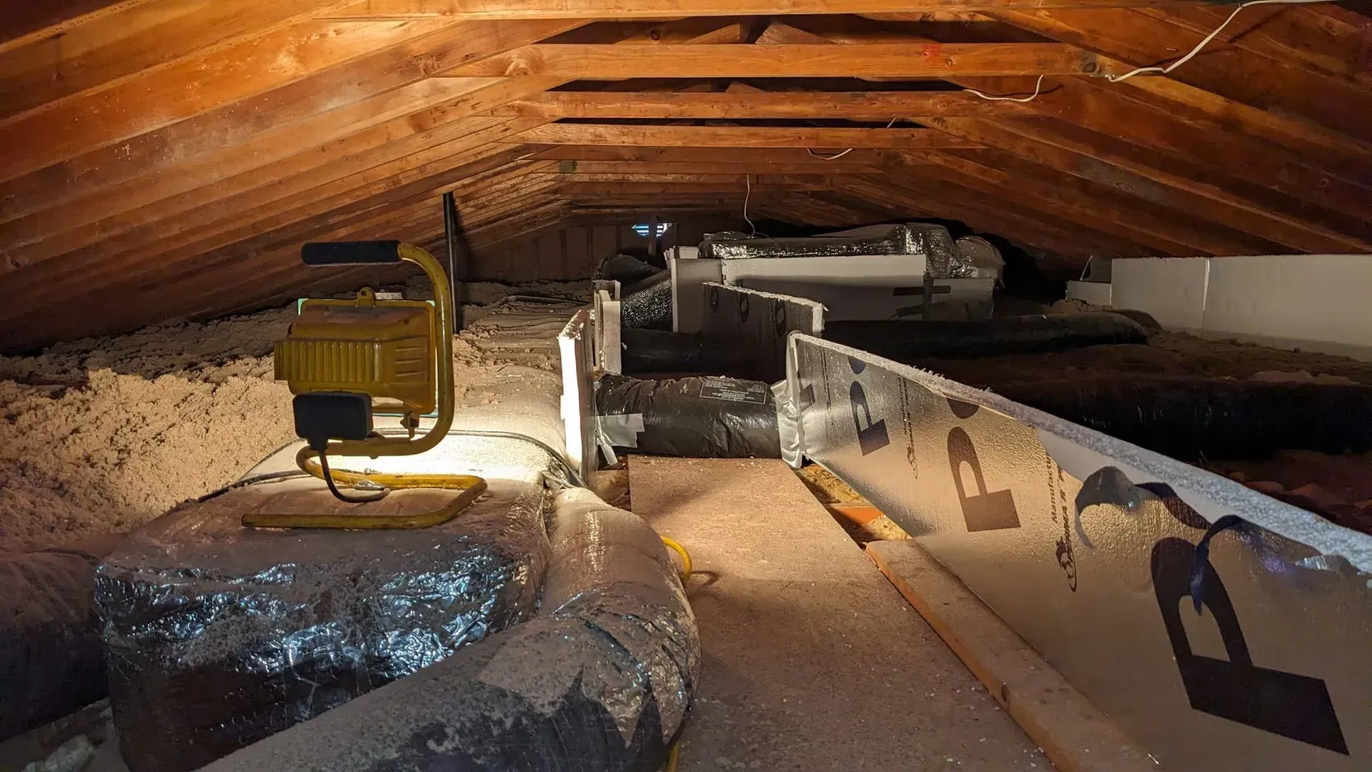 A light is sitting in the attic of a house.