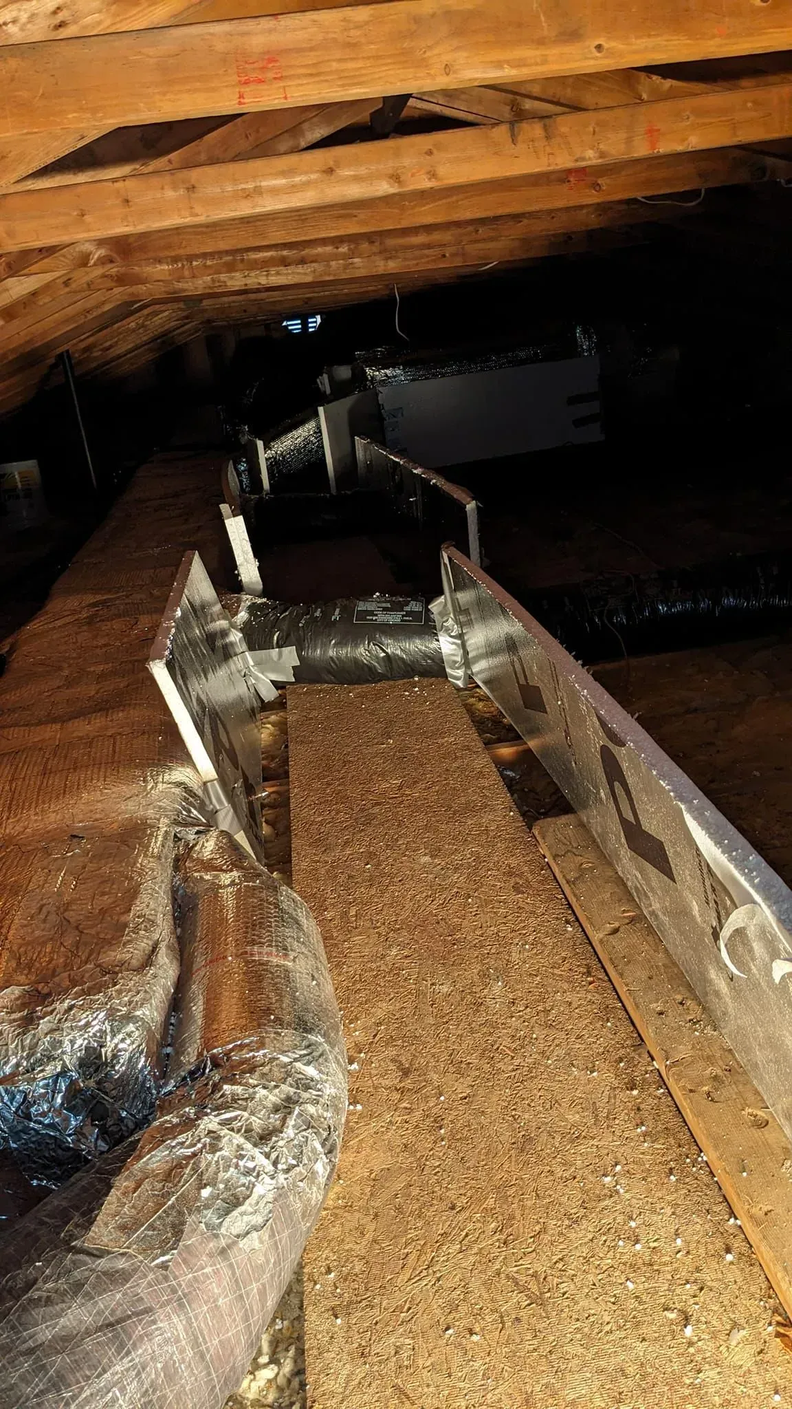 A wooden beam is sitting in the attic of a house.