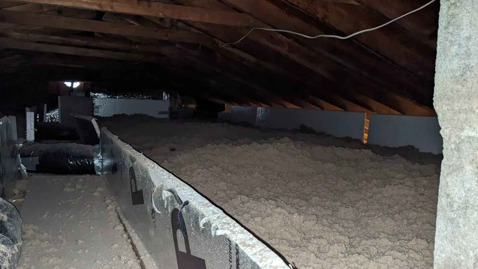 An attic with a lot of wooden beams and a lot of insulation.