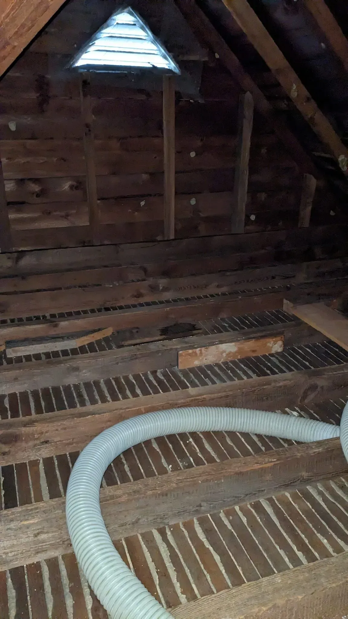 A hose is hanging from the ceiling of an attic.