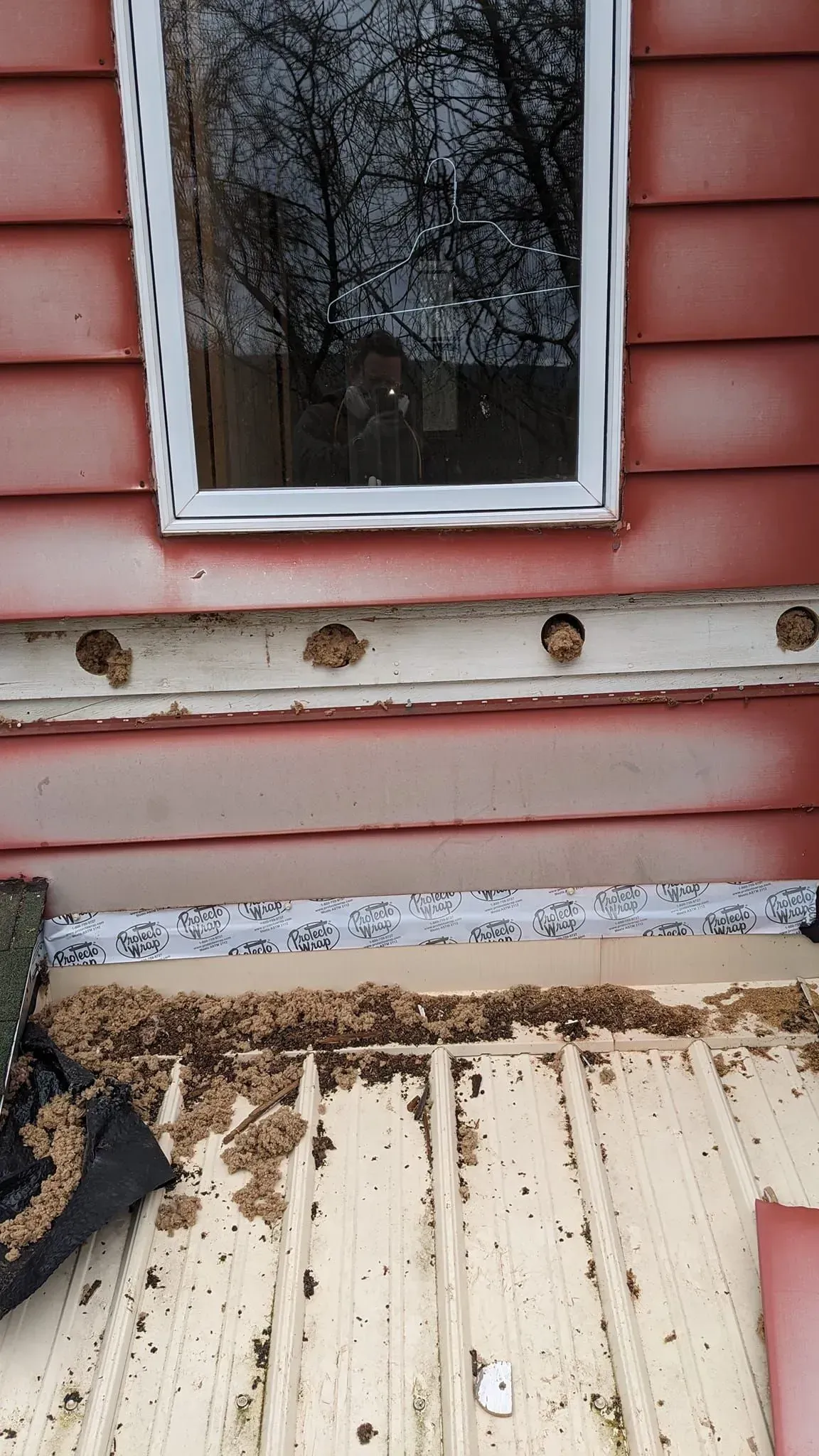 A window on the side of a red house with a white frame.