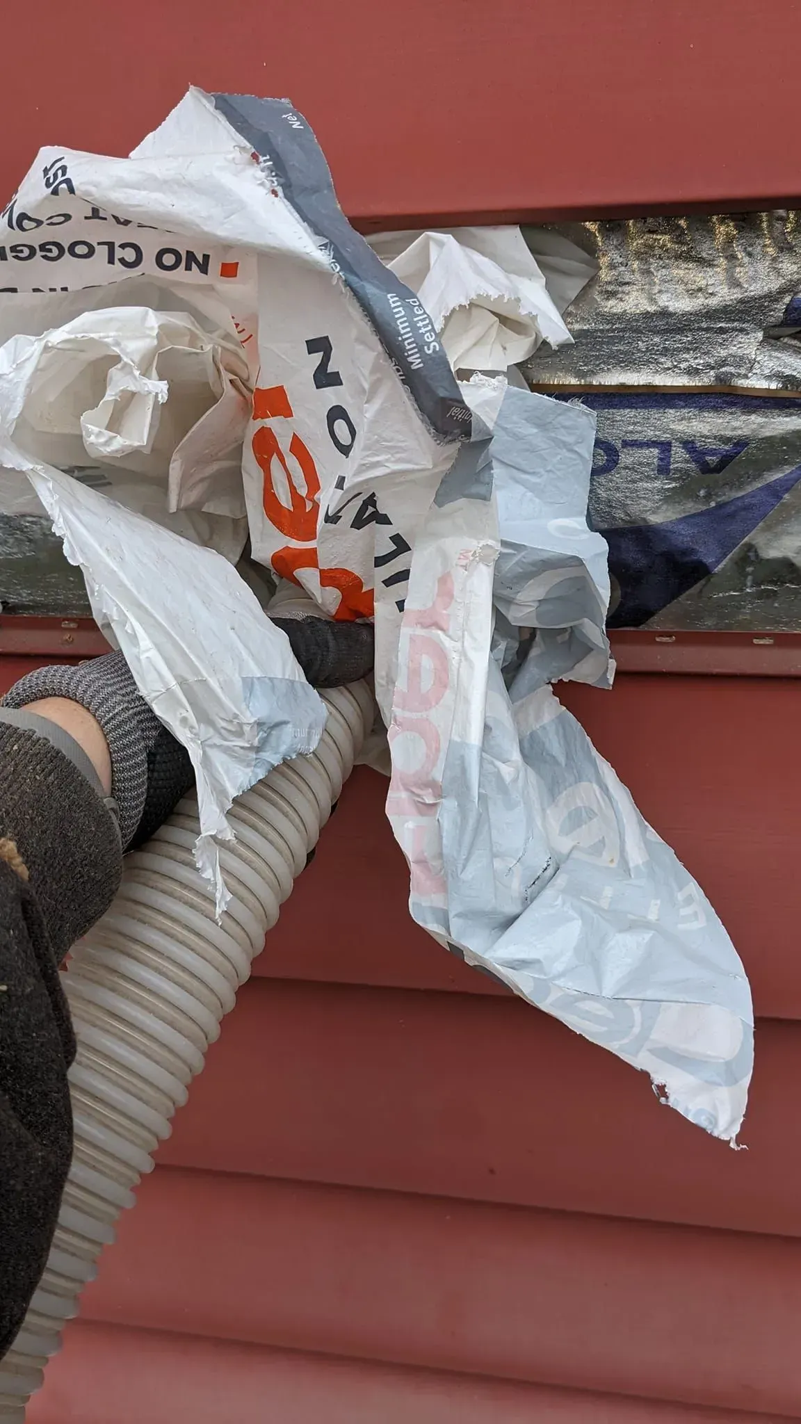 A person is holding a piece of paper in front of a red wall.