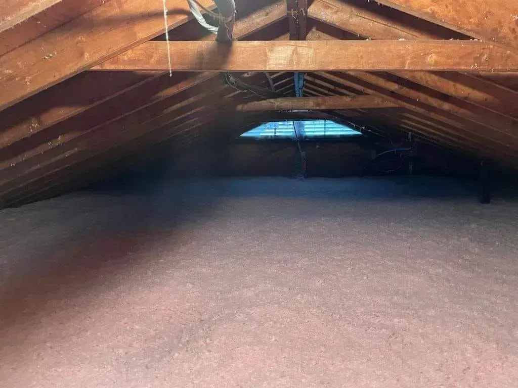 An attic with a lot of insulation and a window.