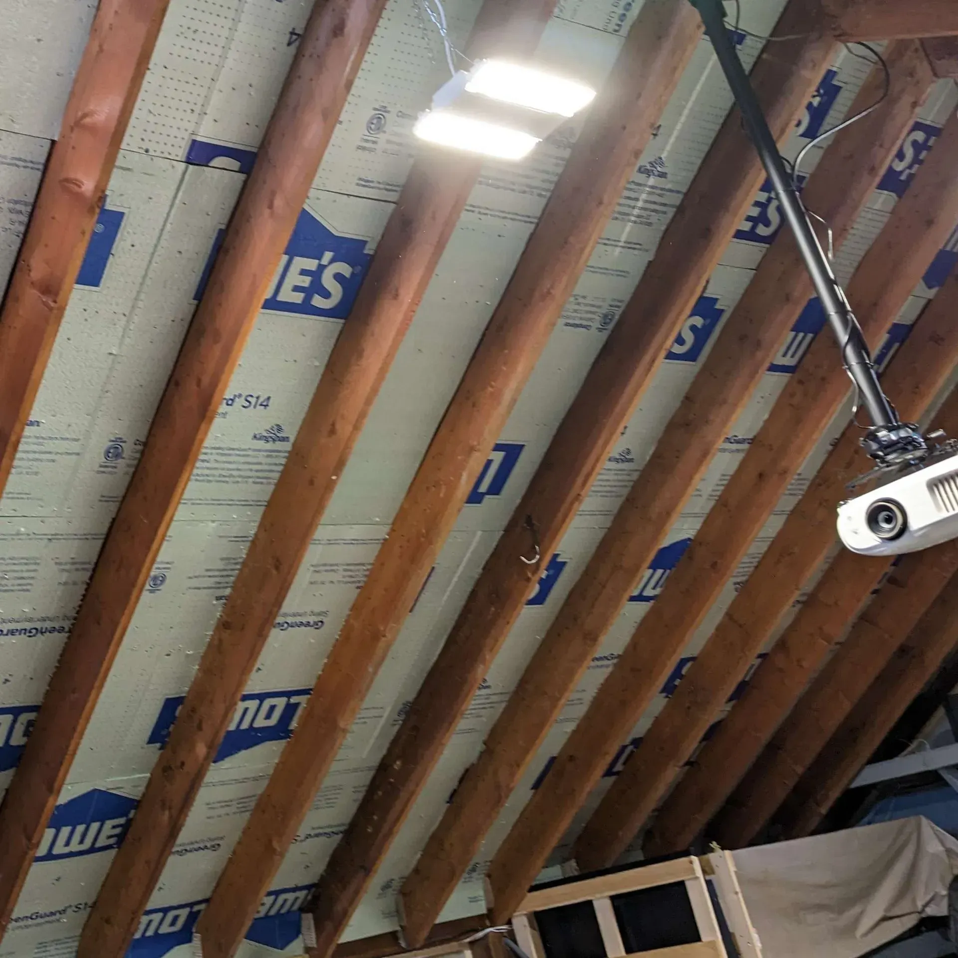 A projector is hanging from the ceiling of a building