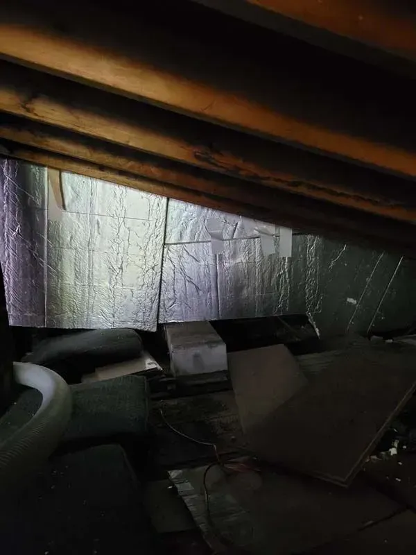 An attic with a lot of insulation and wooden beams.