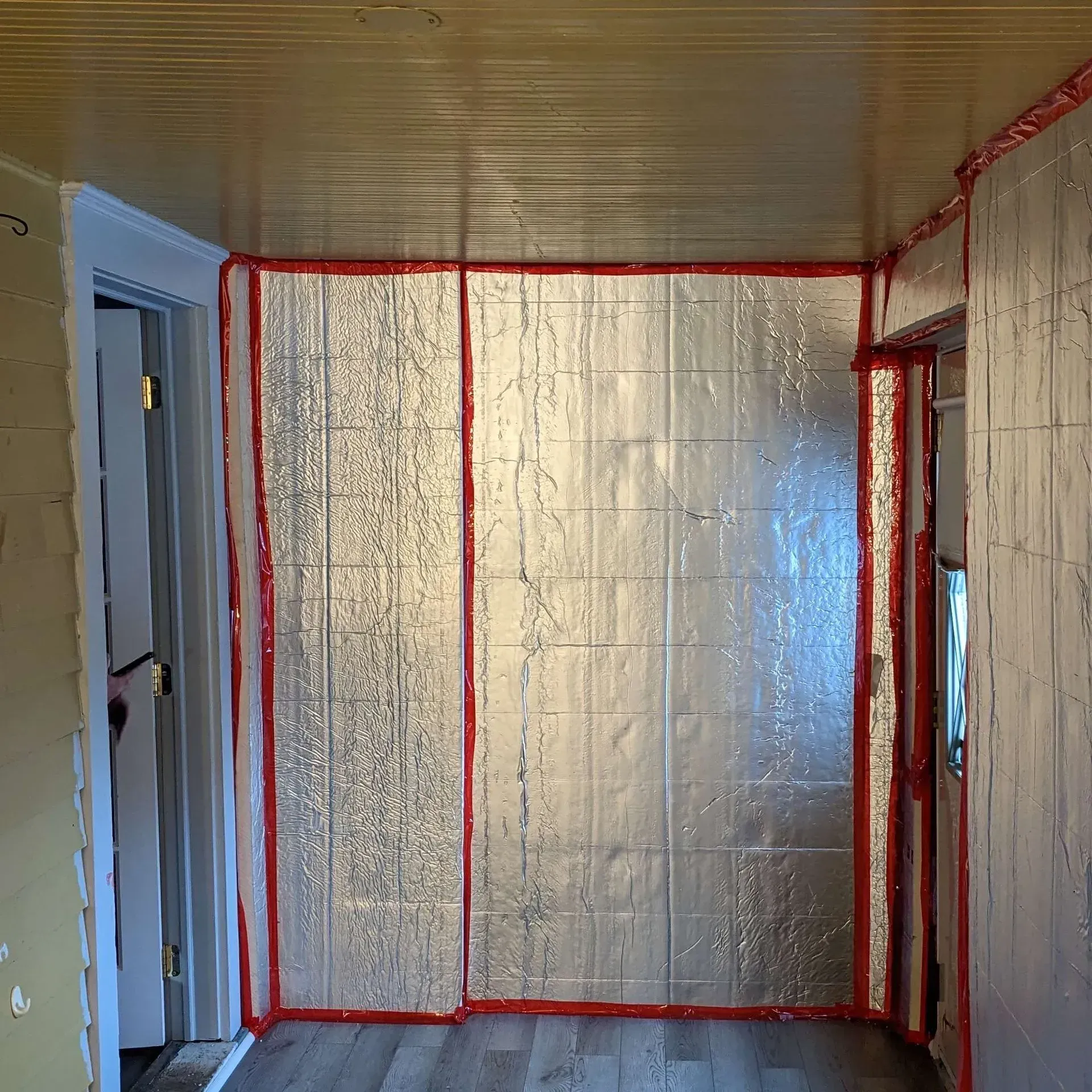 A room with a door and a wall with insulation on it