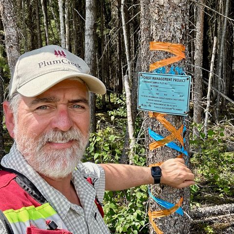 Robert Froese standing beside a tree with a permanent sample plot marker