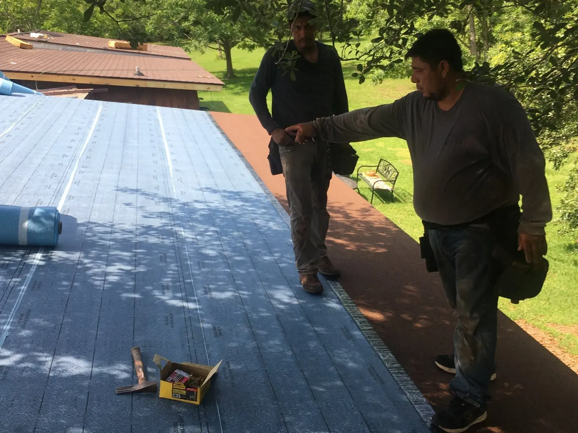 A man wearing a hat is working on a wooden deck.