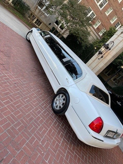 A white limousine is parked on a brick driveway.