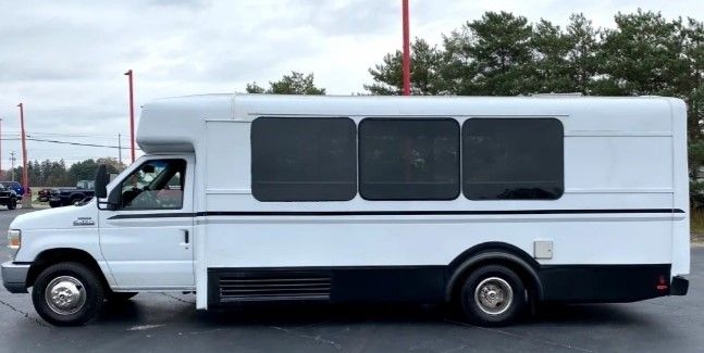 A white bus is parked in a parking lot.