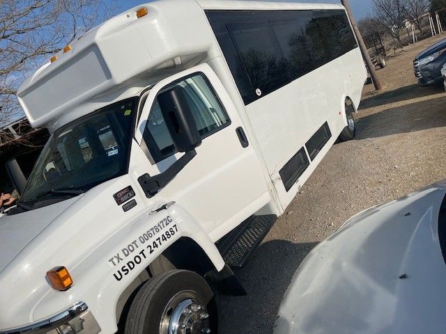 A white bus is parked next to a white car.