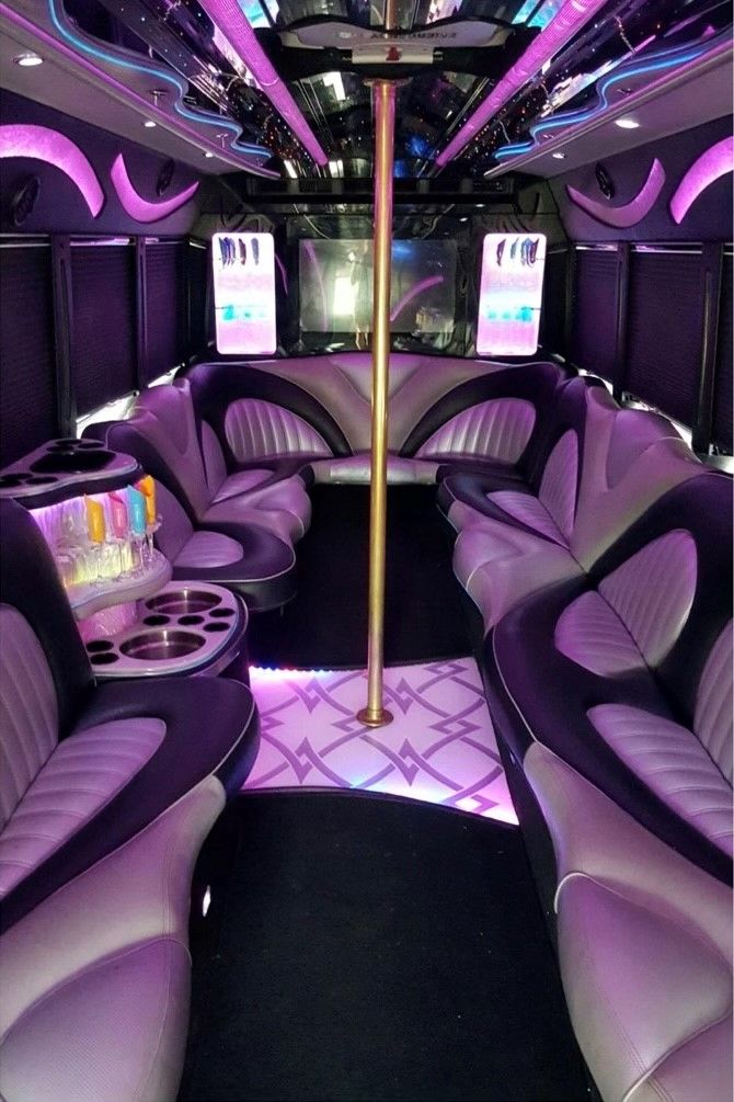 The inside of a limousine with purple seats and a pole.