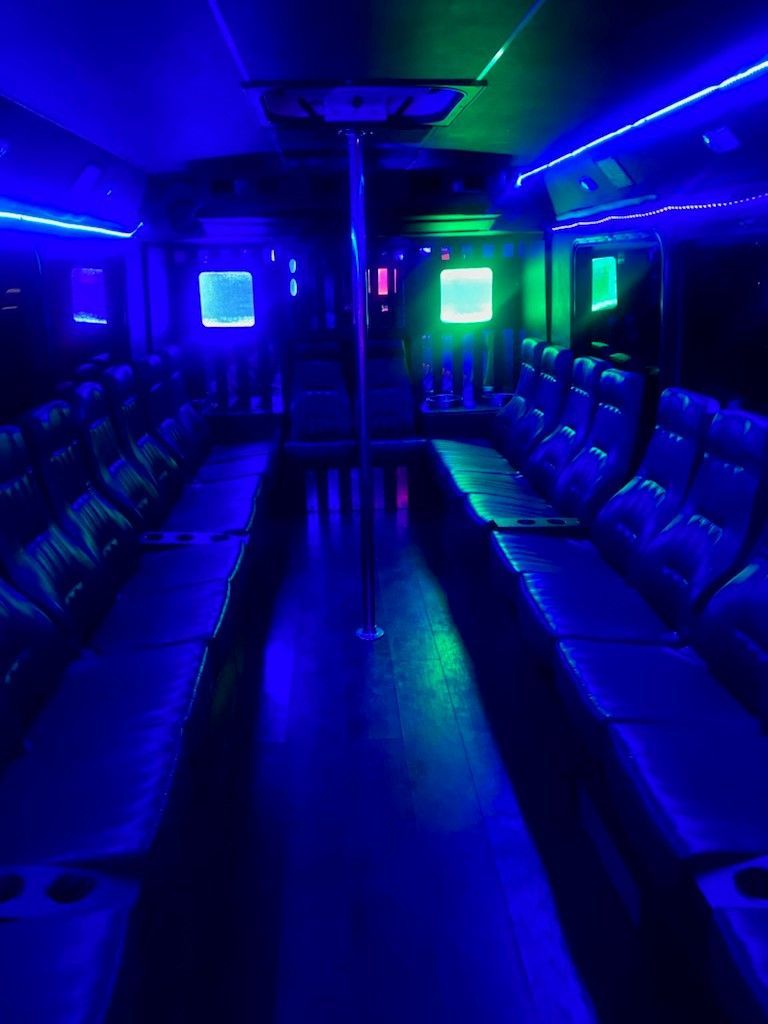 The inside of a bus is lit up with blue and green lights.