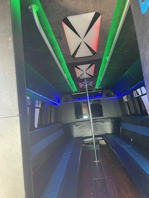 The inside of a shuttle bus with a pole in the middle.