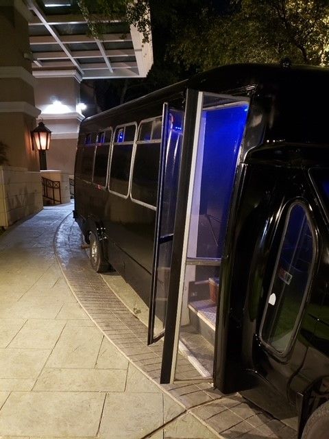 A black bus is parked on the side of the road at night